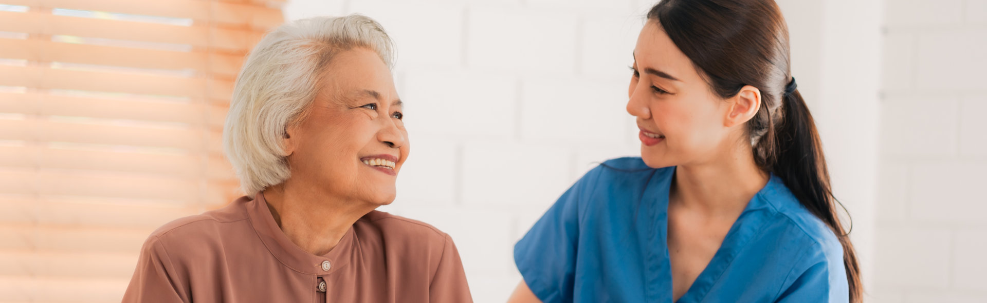 caregiver and an elderly woman smiling together